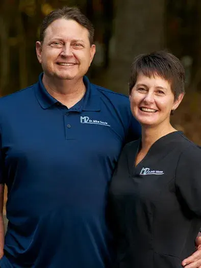 Two dental professionals smiling in blue and black branded shirts at Kernersville dental practice.