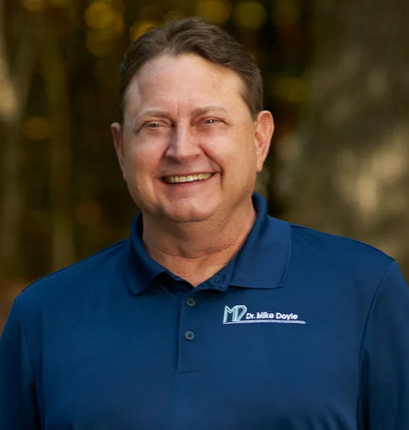 Professional headshot of smiling man in blue polo shirt with dental practice logo, indoor setting.
