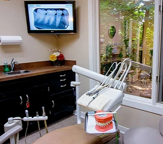 Modern dental operatory with chair, equipment, and X-ray display in contemporary office setting.