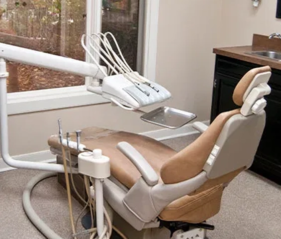 Patient reclined in dental chair during examination in modern dental office treatment room.