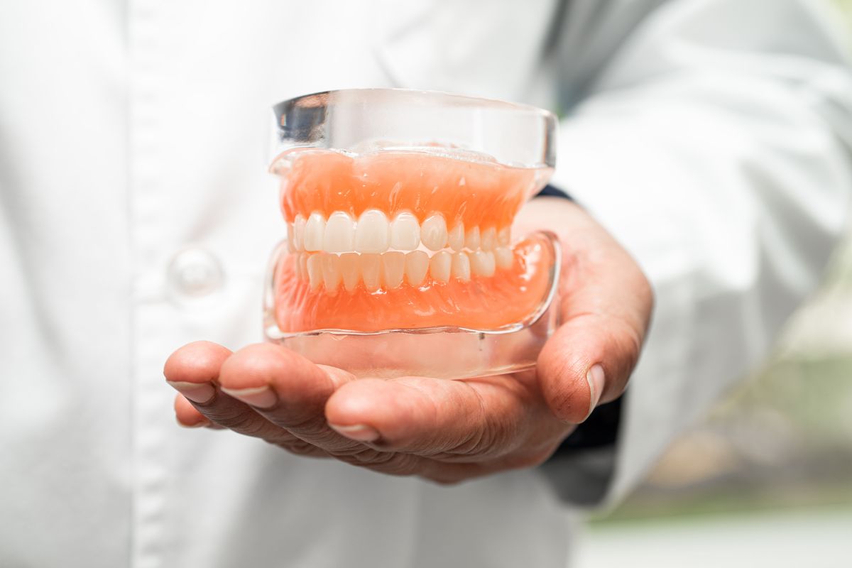 Dentist holding a full set of dentures model demonstrating proper fit and alignment for comfortable eating and speaking