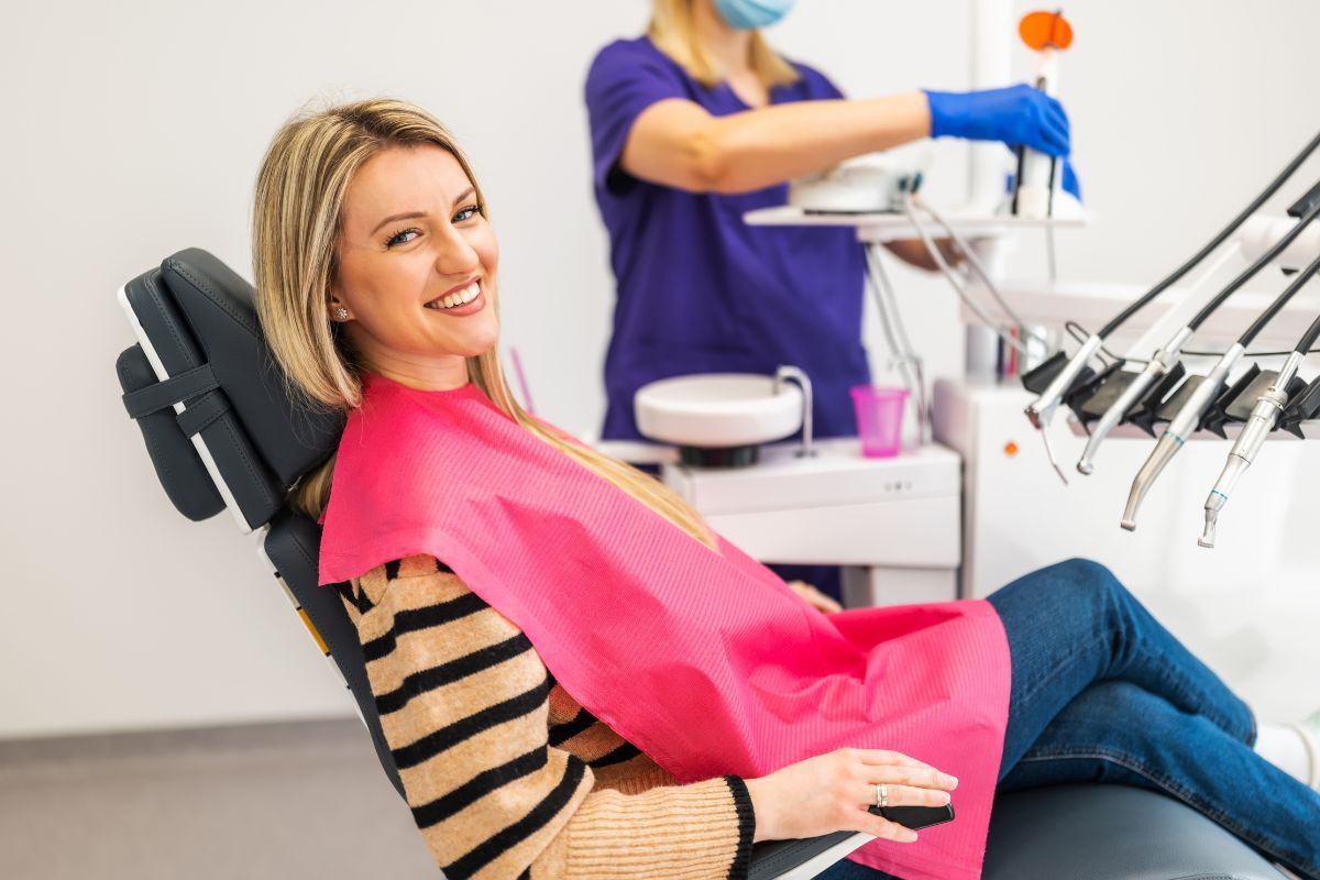Happy patient in dental chair during routine exam at modern dentistry office.