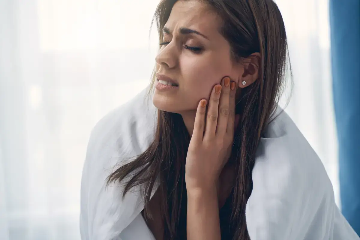 Woman with jaw pain touching her cheek, illustrating tooth discomfort and dental concerns.