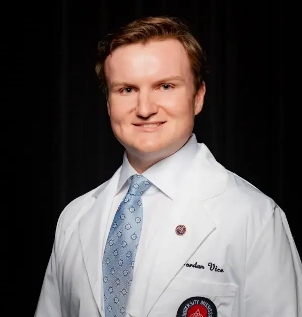Dr. Jordan Vice in professional white coat and blue patterned tie at Kernersville dental practice.