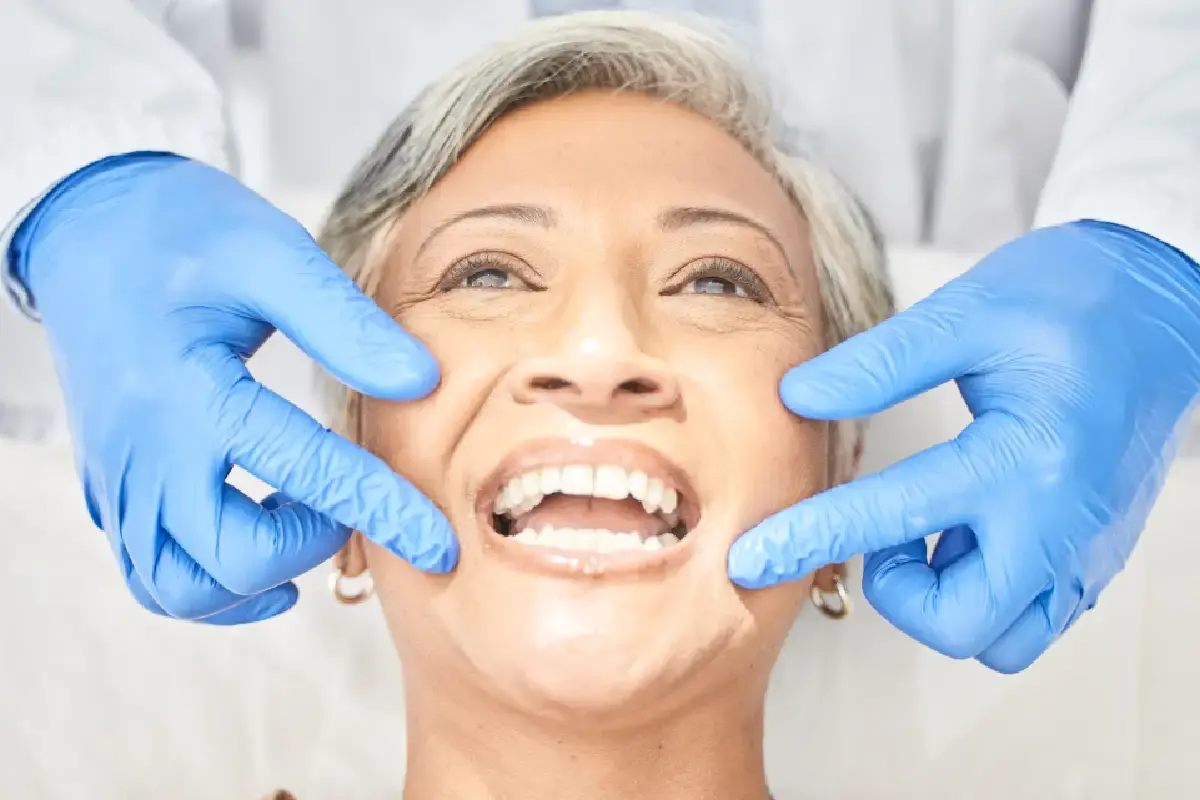 Senior woman smiling while dentist examines her teeth in Kernersville, NC.